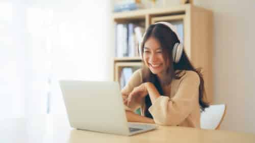 Young asian woman wearing headset while working on computer laptop at house. Work at home, Video conference, Video call, Student learning online class